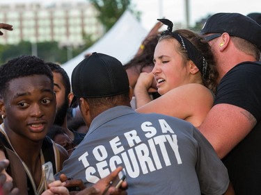 A woman is helped out of the huge crowd waiting for Migos as day seven of the RBC Bluesfest takes place on the grounds of the Canadian War Museum.