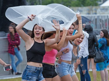 Fans of rapper Fetty Wap gather under a poncho as the rain came as day five of the RBC Bluesfest takes place on the grounds of the Canadian War Museum.