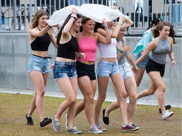 Fans of rapper Fetty Wap gather under a poncho as the rain came as day five of the RBC Bluesfest takes place on the grounds of the Canadian War Museum.