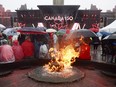People take shelter from the rain on Parliament Hill as the Centennial Flame burns in Ottawa during Canada 150 celebrations on Saturday, July 1, 2017.
