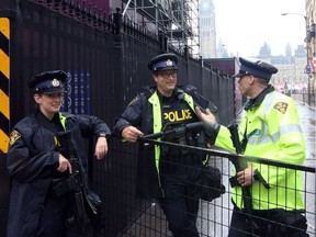 Police officers armed with heavy automatic weapons stand guard a blocked street leading to Parliament Hill in preparation for Canada Day.