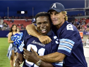 Former Toronto Argonauts players Mike "Pinball" Clemens, left, and Doug Flutie embrace during a ceremony commemorating the 1996-97 CFL championships during halftime of a CFL football game in Toronto, Monday, July 24, 2017.