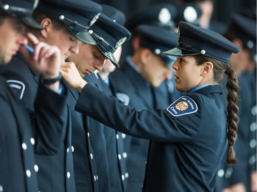 Recruit Helena Inaloz checks on the uniform of her fellow graduates as Ottawa Fire Services hosts a graduation ceremony to welcome its newest probationary firefighters at Ottawa City Hall.