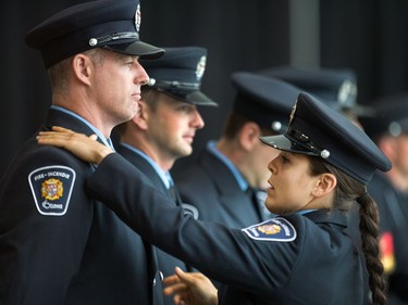 Recruit Helena Inaloz checks on the uniform of her fellow graduate Colin Barrett as Ottawa Fire Services hosts a graduation ceremony to welcome its newest probationary firefighters at Ottawa City Hall.