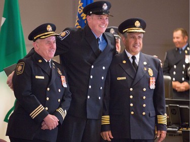 Recruit Seamus Dewan (C) poses with Fire Chief Gerry Pingitore (R) and District Chief Jim Cockram (L) as Ottawa Fire Services hosts a graduation ceremony to welcome its newest probationary firefighters at Ottawa City Hall.