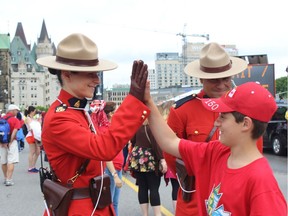 Noam Kaplan-Myrth photographed high-fiving a Mountie in downtown Ottawa on Saturday. Noam's brother art is compiling 150 photos of his brother high-fiving strangers.