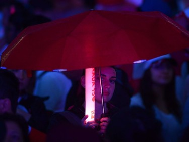 A person shields themselves from the rain as guests await the evening ceremonies for Canada's 150th anniversary of Confederation, in Ottawa on Saturday, July 1, 2017.