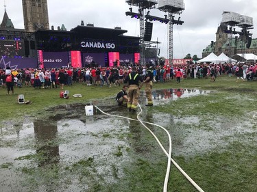 Firefighters pump water off the soggy lawn at Parliament Hill Saturday, Canada Day.