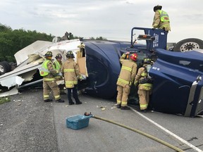 Firefighters work on cleaning up spills following a truck rollover on Highway 417 Friday.