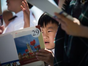 Jason Tian, 7, from China, reads along with the French language portion while taking the oath of citizenship with his brother and mom during a special Canada Day citizenship ceremony in West Vancouver, B.C., on Saturday, July 1, 2017.