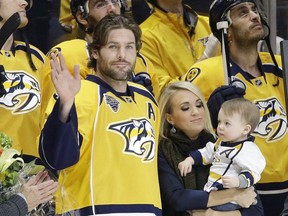 Nashville Predators forward Mike Fisher, beside his wife, singer Carrie Underwood, and their son, Isaiah, waves to the crowd while being honoured for playing his 1,000th career NHL game.