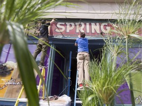 Tom Pajdlhauser, left, and Andrew King, remove an old Pure Spring Ginger Ale sign over a shop at the corner of Somerset St and Bronson Ave Wednesday.