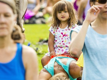 Carmen Maciag, 2, sits on her mom, Cassandra, as hundreds of people take part in the last yoga on Parliament Hill event hosted by Lululemon Athletica Wednesday, August 30, 2017.
