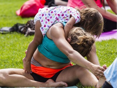 Carmen Maciag, 2, crawls over her mom, Cassandra, as hundreds of people take part in the last yoga on Parliament Hill event hosted by Lululemon Athletica Wednesday, August 30, 2017.