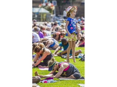 Evie Bolton jumps off her mom, Lynz Bolton, while she does yoga with hundreds in the last yoga on Parliament Hill event hosted by Lululemon Athletica Wednesday, August 30, 2017.
