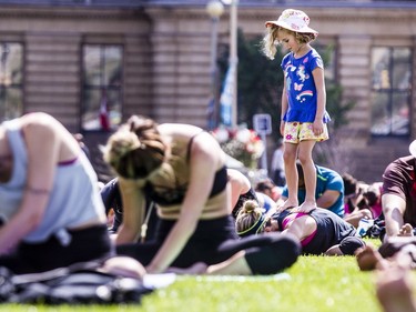 Evie Bolton stands on her mom, Lynz Bolton, while she does yoga with hundreds in the last yoga on Parliament Hill event hosted by Lululemon Athletica Wednesday, August 30, 2017.