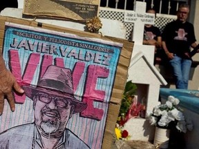 In this July 1, 2017 photo, relatives of slain journalist Javier Valdez, co-founder of Riodoce, stand at a memorial set up at the spot where he was murdered in Culiacan, Sinaloa state, Mexico. On the morning of May 15, Valdez left his Riodoce office and managed to drive just a couple of blocks before his red Toyota Corolla was stopped by two men; he was forced out of his car and shot 12 times. (AP Photo/Enric Marti)