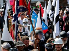 FILE - In this Saturday, Aug. 12, 2017, file photo, white nationalist demonstrators walk into the entrance of Lee Park surrounded by counter demonstrators in Charlottesville, Va. People are using social media to identify and shame white nationalists who attended this past weekend‚Äôs gathering in Charlottesville. At least one person has reportedly been fired as a result, showing that the power of angry online mobs can go both ways. (AP Photo/Steve Helber, File)