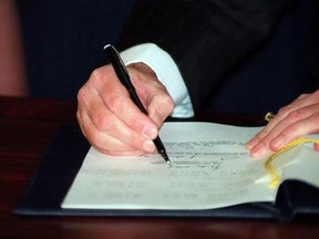 Prime Minister Brian Mulroney signs the North American Free Trade Agreement during a signing ceremony in Ottawa on December 17, 1992. THE CANADIAN PRESS/Tom Hanson