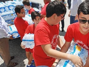 Incarnate Word Academy (IWA) 7th graders in Brownsville, Texas, unload a truck of donated bottled water Tuesday, Aug. 29, 2017, as IWA hopes to fill an 18 wheeler trailer with community donated supplies to its final destination in Houston where Hurricane Harvey devastated Houstonians. (Miguel Roberts/The Brownsville Herald via AP)