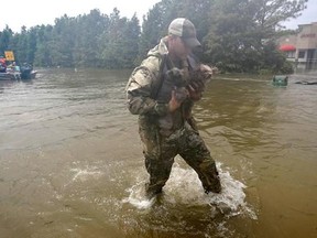 A rescue worker carries two dogs to safety after evacuating their family from floodwaters from Tropical Storm Harvey Sunday, Aug. 27, 2017, in Houston, Texas. A small group of Canadian volunteers will be heading to Houston to rescue dogs from shelters that have been overwhelmed after a hurricane hit the city. THE CANADIAN PRESS/AP-David J. Phillip