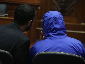 In this July 31, 2014 file photo, a Syrian Army defector (blue hooded jacket) who smuggled 50,000 photographs out of Syria documenting the torture and execution of more than 10,000 dissidents, listens to an interpreter during a briefing before the House Foreign Affairs Committee on Capitol Hill in Washington. A paper trail, the authors say, mean there could be justice found for Syria's dead and tortured. (Alex Wong, Getty Images)