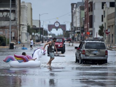 People make their way down partially flooded roads following the passage of Hurricane Harvey on August 26, 2017 in Galveston, Texas.