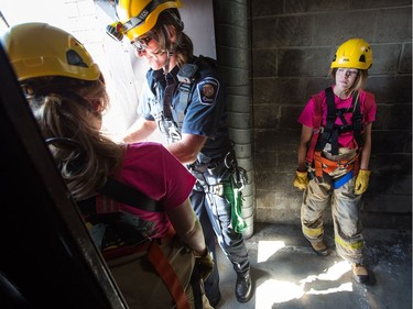 While firefighter John Pomeroy prepares another camper, Grace Leslie (R) looks a little nervous as she prepares to rappel down the side of the tower from about the fifth floor as the week long Camp FFIT continues at the Ottawa Fire Services Training Centre on Industrial Ave where teenage girls are educated about the career of firefighting. Participants took part in Search and Rescue, Auto extrication, Forcible entry, Catching hydrants, High rise operations, rappelling, and aerial ladder climb among other things.