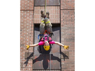 Kayla Brunetta hangs inverted while rappelling down the tower as the week long Camp FFIT continues at the Ottawa Fire Services Training Centre on Industrial Ave where teenage girls are educated about the career of firefighting. Participants took part in Search and Rescue, Auto extrication, Forcible entry, Catching hydrants, High rise operations, rappelling, and aerial ladder climb among other things.