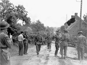 Major David V. Currie (left, with pistol in hand) of The South Alberta Regiment accepting the surrender of German troops at St. Lambert-sur-Dives, France, 19 August 1944. This photo captures the very moment and actions that would lead to Major Currie being awarded the Victoria Cross.  Source: Library and Archives Canada