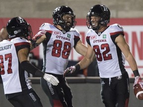 Redblacks wide receiver Greg Ellingson, right, celebrates with Josh Stangby, left, and Brad Sinopoli after making a fourth-quarter touchdown catch against the Alouettes on Thursday night. THE CANADIAN PRESS/Paul Chiasson