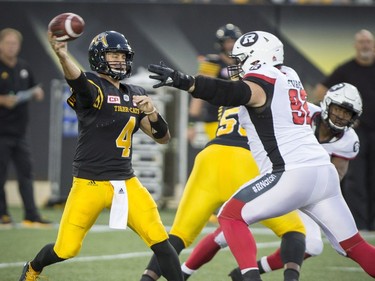 Tiger-Cats quarterback Zach Collaros (4) throws while being pressured by Redblacks defensive lineman Zack Evans. THE CANADIAN PRESS/Peter Power