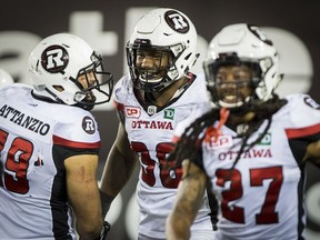There's reason to smile for Redblacks defensive lineman Avery Ellis (98) after he recovers a fumble and runs into the end-zone for a fourth-quarter touchdown on Friday night. At left is fellow defensive lineman Ettore Lattanzio, and at right is defensive back Sherrod Baltimore. THE CANADIAN PRESS/Peter Power