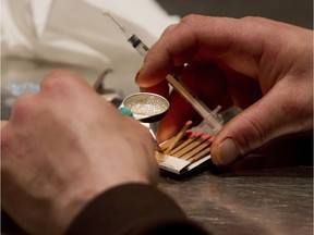 In this file photo, a man prepares heroin he bought on the street to be injected at the Insite safe injection clinic in Vancouver.