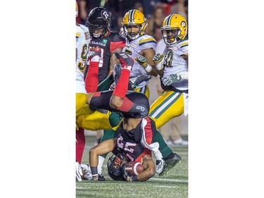 Redblacks tailback Mossis Madu is upended by Eskimos defenders in the second quarter.  Wayne Cuddington/Postmedia