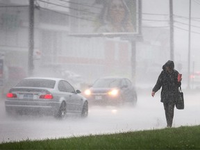 A woman trudges along Merivale Rd as a thunderstorm passes over blanketing the region with a deluge of rain for about twenty minutes.
