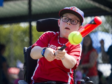 Eight-year-old Jackson Hamilton hits the ball to send it flying during the Miracle League-police game.