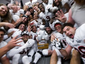 Ravens players celebrate with the Pedro the Panda trophy after winning 33-30 in overtime against the Gee-Gees on Saturday.   Ashley Fraser/Postmedia