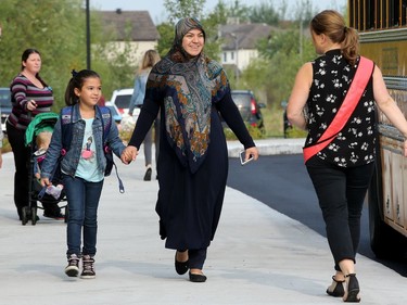 Aya Serene (centre) says hi to a familiar teacher as she drops off her daughter, Fatima El-Cheikh, 8, and brother, Jaward Serene, 13.  It was the first day back at school for kids in Ottawa's public board Tuesday (Sept. 5, 2017). However, for almost 600 children, it was their first day at a new school, Vimy Ridge Public School, which opened Tuesday in Findlay Creek and held an opening ceremony outside, complete with a flag raising and veteran bagpiper.  Julie Oliver/Postmedia
Julie Oliver, Postmedia