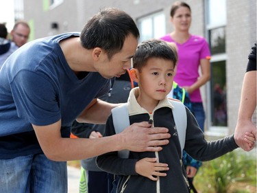 Lou Yuan Lin reassures his son, Kevin Lin, 6, as he is led away by his teacher into the school. It was the first day back at school for kids in Ottawa's public board Tuesday (Sept. 5, 2017). However, for almost 600 children, it was their first day at a new school, Vimy Ridge Public School, which opened Tuesday in Findlay Creek and held an opening ceremony outside, complete with a flag raising and veteran bagpiper.  Julie Oliver/Postmedia
Julie Oliver, Postmedia