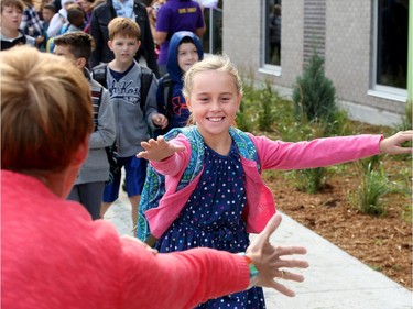 Cara Perrault, 8, gets one last high five from her mom, Christine, as she walks into the school for class. It was the first day back at school for kids in Ottawa's public board Tuesday (Sept. 5, 2017). However, for almost 600 children, it was their first day at a new school, Vimy Ridge Public School, which opened Tuesday in Findlay Creek and held an opening ceremony outside, complete with a flag raising and veteran bagpiper.  Julie Oliver/Postmedia
Julie Oliver, Postmedia