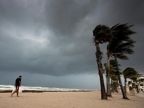 A man walks along the beach with heavy winds and threatening skies in anticipation for Hurricane Irma, in Hollywood, Fla., Saturday, September 9, 2017. THE CANADIAN PRESS/Paul Chiasson