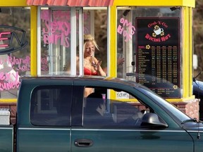 FILE - In this Feb. 2, 2010, file photo, a barista at a Grab-N-Go Bikini Hut espresso stand holds money as she waves to a customer, just outside the city limits of Everett, Wash., in Snohomish County. Seven bikini baristas and the owner of a chain of the coffee stands called &ampquot;Hillbilly Hotties&ampquot; sued the city of Everett, Washington, on Monday, Sept. 11, 2017, saying two recently passed ordinances banning bare skin violate their right to free expression. The proprietor of another chain, the Grab-N