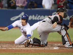 Darwin Barney #18 of the Toronto Blue Jays slides across home plate to score the game-winning run on an RBI single by Richard Urena #7 in the ninth inning during MLB game action against the Baltimore Orioles at Rogers Centre on September 12, 2017 in Toronto.