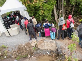 A long line of asylum seekers wait to illegally cross the Canada/US border near Champlain, New York on August 6, 2017. In recent days the number of people illegally crossing the border has grown into the hundreds.