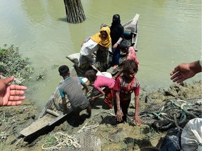 Local Bangladeshis help Rohingya Muslim refugees to disembark from a boat on the Bangladeshi side of Naf river near the Bangladeshi town of Teknaf on September 11, 2017. The number of Rohingya who have fled violence in Myanmar's Rakhine state and entered Bangladesh since August 25 has reached 313,000, a UN spokesman said on September 11. / AFP PHOTO / MUNIR UZ ZAMANMUNIR UZ ZAMAN/AFP/Getty Images MUNIR UZ ZAMAN, AFP/Getty Images