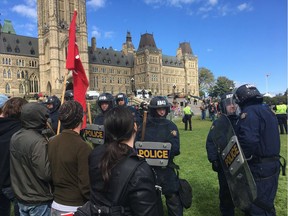 Riot police keep counter-protesters away from a group protesting Canadian immigration policy Saturday.