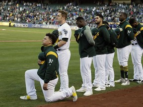Oakland Athletics catcher Bruce Maxwell kneels during the National Anthem before the start of a baseball game against the Texas Rangers Saturday, Sept. 23, 2017, in Oakland, Calif. Bruce Maxwell of the Oakland Athletics has become the first major league baseball player to kneel during the national anthem.