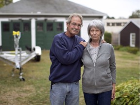 In this Oct. 10, 2013 file photo, David and Beth Henneberry pose in the backyard of their Watertown, Mass., home with a new boat trailer used for a new boat. David Henneberry, who found surviving Boston Marathon bomber Dzhokhar Tsarnaev hiding in his boat in his backyard, died Wednesday, Sept. 27, 2017. He was 70.