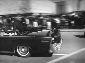 FILE - In this Nov. 22, 1963 file photo, the limousine carrying mortally wounded President John F. Kennedy races toward the hospital seconds after he was shot in Dallas. Secret Service agent Clinton Hill is riding on the back of the car, Nellie Connally, wife of Texas Gov. John Connally, bends over her wounded husband, and first lady Jacqueline Kennedy leans over the president. The National Archives has until Oct. 26, 2017, to disclose the remaining files related to Kennedy's assassination, unless President Donald Trump intervenes. (AP Photo/Justin Newman, File)